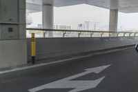 white arrows painted on the side of an empty road next to tall buildings, viewed out of a moving car window