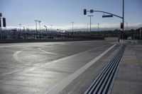 empty street and two rows of benches at a crosswalk intersection under traffic lights at an intersection