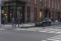 the buildings of a business district can be seen along an empty street with pedestrians crossing