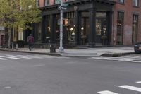 the buildings of a business district can be seen along an empty street with pedestrians crossing