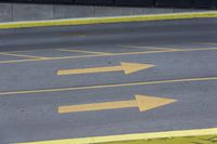 some yellow arrows are in the pavement pointing to left, and to right, on a sidewalk in front of some buildings