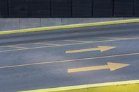 some yellow arrows are in the pavement pointing to left, and to right, on a sidewalk in front of some buildings