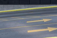some yellow arrows are in the pavement pointing to left, and to right, on a sidewalk in front of some buildings