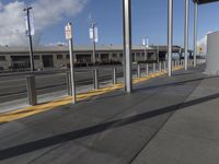 a public area with parking spaces and cars at it, a train station with several metal posts