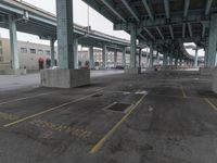 an empty parking lot with a lot of parked cars underneath it with overpasses