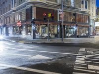 a city street at night with an empty pedestrian crosswalk lit up by the light of a stoplight