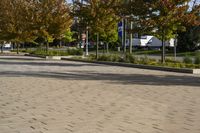 a city area with trees and paved concrete in the foreground with blue sky and sun