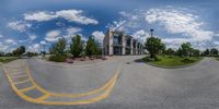 a fish eye view of a road and church in the distance and a car in front