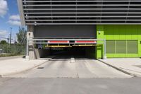 an overpass at the side of a large building with a green door leading to a yellow car garage