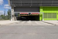 an overpass at the side of a large building with a green door leading to a yellow car garage