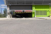 an overpass at the side of a large building with a green door leading to a yellow car garage