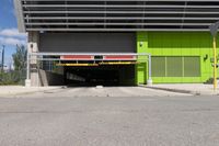 an overpass at the side of a large building with a green door leading to a yellow car garage