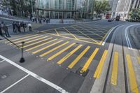 an aerial shot of people walking on the street at an intersection with yellow markings and lines