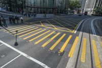 an aerial shot of people walking on the street at an intersection with yellow markings and lines