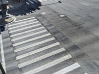 this is an intersection where there are white lines and crossing painted in greys with two black dots