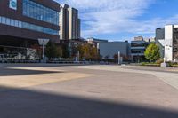 a skateboarder rides down an empty sidewalk in front of a large building with trees