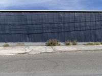 black building next to pavement with fenced in area on corner of street and grass