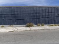 black building next to pavement with fenced in area on corner of street and grass