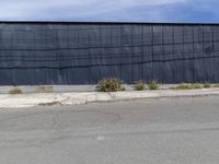 black building next to pavement with fenced in area on corner of street and grass