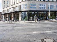 a bunch of bikes sit parked on the corner of a street near an office building