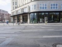 a bunch of bikes sit parked on the corner of a street near an office building