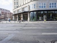 a bunch of bikes sit parked on the corner of a street near an office building
