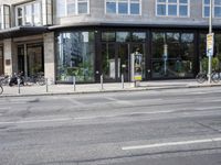 a bunch of bikes sit parked on the corner of a street near an office building