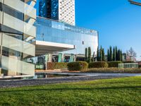 an outdoor bench on the side of a building, with a very large glass building in the background