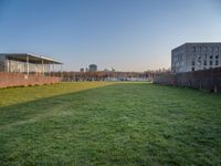 this grass field has been cut short to cover the area in the distance, and it is a grassy area next to an old building