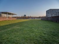 this grass field has been cut short to cover the area in the distance, and it is a grassy area next to an old building