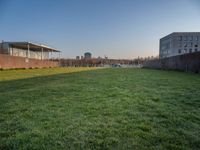 this grass field has been cut short to cover the area in the distance, and it is a grassy area next to an old building