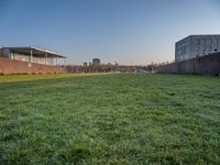 this grass field has been cut short to cover the area in the distance, and it is a grassy area next to an old building