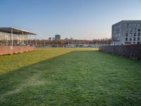 this grass field has been cut short to cover the area in the distance, and it is a grassy area next to an old building