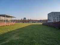 this grass field has been cut short to cover the area in the distance, and it is a grassy area next to an old building