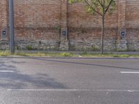 the boy is skateboarding on the side of the street beside an older brick building