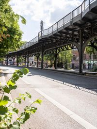 street under the bridge with several people walking on it's sides as well as trees