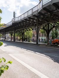 street under the bridge with several people walking on it's sides as well as trees