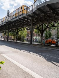 street under the bridge with several people walking on it's sides as well as trees