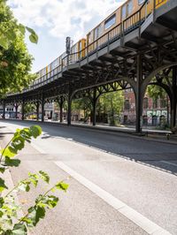 street under the bridge with several people walking on it's sides as well as trees