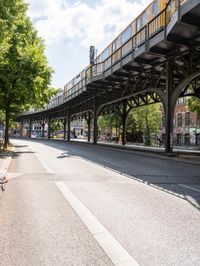 street under the bridge with several people walking on it's sides as well as trees