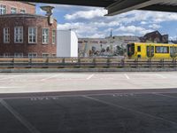 yellow and silver train at train station with graffiti in background and buildings and blue sky