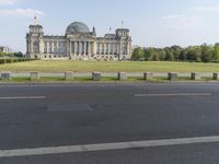 a view of a huge building in the middle of the park area and street signs