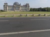 a view of a huge building in the middle of the park area and street signs