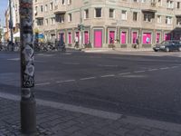 a pole has some stickers on it at an intersection with buildings in the background