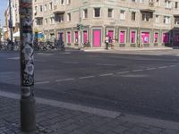 a pole has some stickers on it at an intersection with buildings in the background