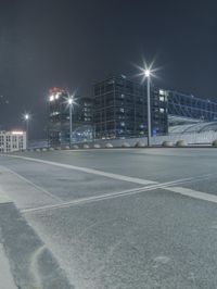 the empty city road is empty by the tall building in the background at night with light streaking on the buildings