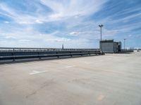 an empty parking lot with metal stairs leading down to a building in the background and bright blue sky