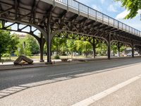 a bridge is on a street in the city with a bike beside it and benches under it