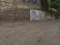 a graffiti wall has been vandalized by a dog and two people sitting on the street