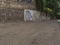 a graffiti wall has been vandalized by a dog and two people sitting on the street